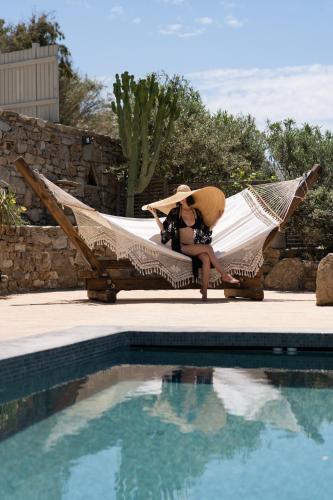 a woman sitting in a hammock next to a pool at Ikies of Mykonos in Mýkonos City