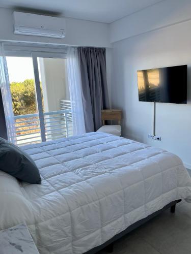 a bedroom with a large white bed and a window at Departamento Costa Esmeralda in Costa Esmeralda