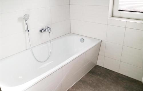uma banheira branca numa casa de banho com azulejos brancos em 2 Bedroom Stunning Home In Rostock-rvershagen em Rövershagen