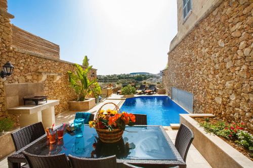 a patio with a table and a swimming pool at Carini Farmhouses in Għarb