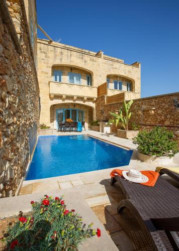a house with a swimming pool in front of a building at Carini Farmhouses in Għarb