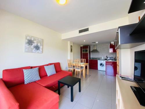 ein Wohnzimmer mit einem roten Sofa und einer Küche in der Unterkunft Relax LUX apartment on Fenals beach in Lloret de Mar