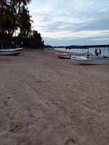 a group of boats on a sandy beach at Vibushan Guest House in Nilaveli