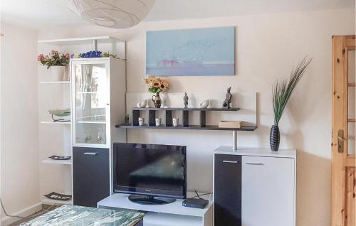 a living room with a tv and a desk with a monitor at 1 Bedroom Awesome Apartment In Bastorf in Bastorf