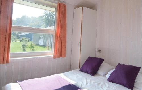 a bed with purple pillows in a room with a window at Strandblick 23 - Dorf 1 in Travemünde