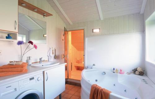 ein Badezimmer mit einer Badewanne, einem Waschbecken und einer Waschmaschine in der Unterkunft Strandblick 23 - Dorf 1 in Travemünde