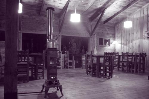 an empty room with a stove and tables and chairs at Las Pitras Lodge in Epuyén