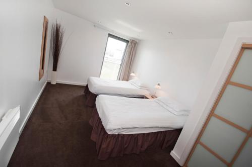 two beds in a room with a window at Ocean Serviced Apartments in Edinburgh