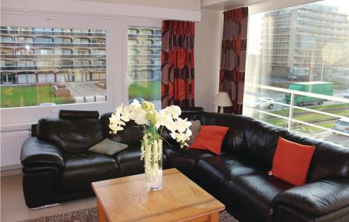 a living room with a black leather couch and a vase with flowers at Residentie Versailles Ref 195 in Ostend