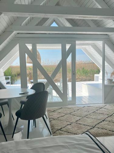 a room with a table and chairs and a view of the ocean at Seehütte Neusiedlersee - Strandhaus, Elektroboot inklusive in Rust