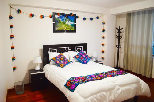 1 dormitorio con 1 cama blanca grande con almohadas coloridas en Qolmay Hostel Cusco en Cusco