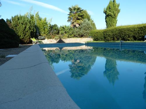 un bassin d'eau bleue planté d'arbres et de buissons dans l'établissement Chambres d'hôtes Le Saleix, à Donzenac