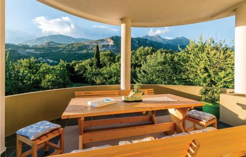 einen Holztisch und Stühle auf einem Balkon mit Bergblick in der Unterkunft Pet Friendly Apartment In Herceg Novi in Herceg-Novi