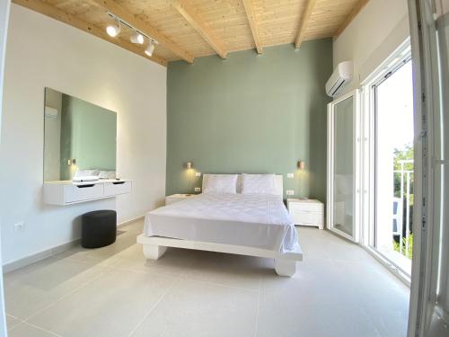 a white bedroom with a white bed and a mirror at Alexander studio in Spartia
