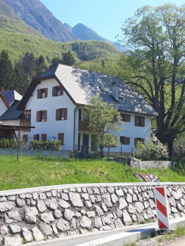 a white house with a stone wall next to a mountain at MMMM in Bovec