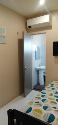 a bedroom with a bed and a bathroom with a sink at Claytown Pension House in Dumaguete