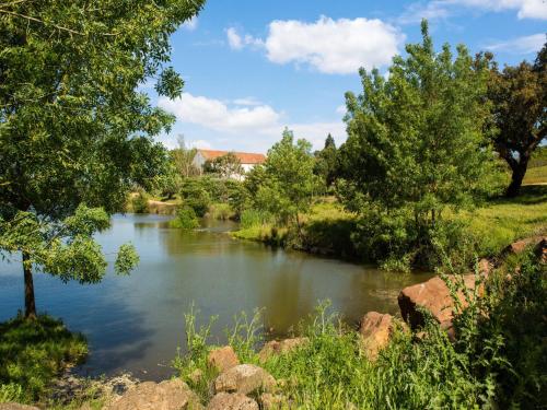 un río con árboles y una casa en el fondo en Country mansion in Montemor o Novo Alentejo with shared pool en Montemor-o-Novo