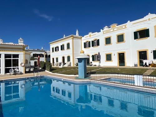 a swimming pool in front of a large building at Relaxing 2 Bedroom House 5 minutes away from Vilamoura Marina in Quarteira