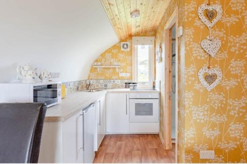 a kitchen with an orange wall with hearts on it at Beautiful couples retreat with hot tub, central heating and views- The Bee Hive by Get Better Getaways in Glenluce