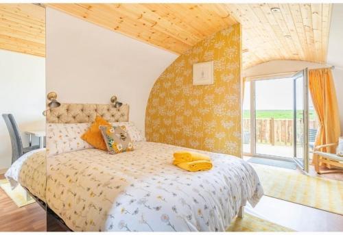 a bedroom with a bed with yellow towels on it at Beautiful couples retreat with hot tub, central heating and views- The Bee Hive by Get Better Getaways in Glenluce