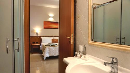 un bagno con lavandino e una camera con letto di Hotel Residence Piccolo a Parghelia