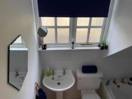 Un baño con lavabo, inodoro y ventana. en House - Sleeps 4 Pet Friendly & Free Parking, en Symington