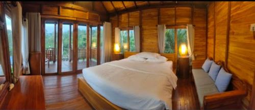 una camera da letto con un letto in una stanza con finestre di Umah Legenda Bali - Legend House Bali a Tabanan
