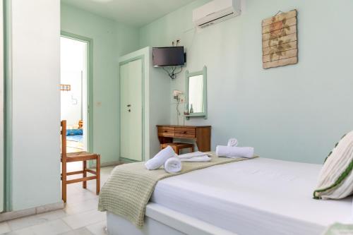 een witte slaapkamer met een bed en een stoel bij Studios Naxos in Naxos Chora