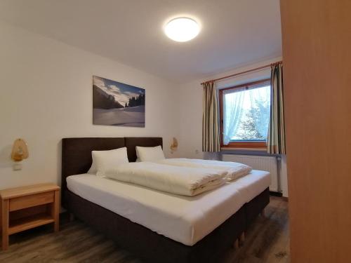 een slaapkamer met een groot bed en een raam bij Appartement Ebster in Pettneu am Arlberg