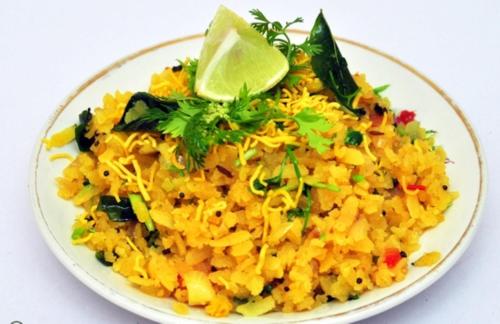 a plate of yellow rice with a lime on top at Dream House Mahabaleshwar in Mahabaleshwar