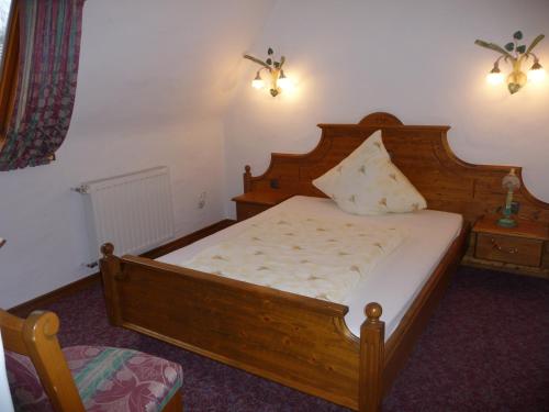 a bedroom with a wooden bed and a night stand at Hotel Haus Tiefenbach in Bullange