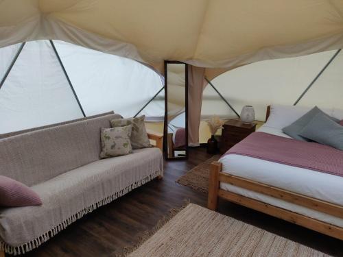 ScrevetonにあるMeadow Vale Retreatsのベッド1台とテント内のソファが備わる客室です。