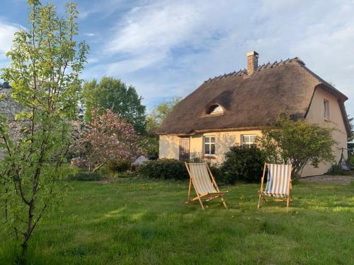 two chairs sitting in the grass in front of a house at OAZA POD STRZECHĄ Klimatyczny dom z 3 sypialniami na wyłączność z kominkiem i dużym ogrodem in Ustronie Morskie