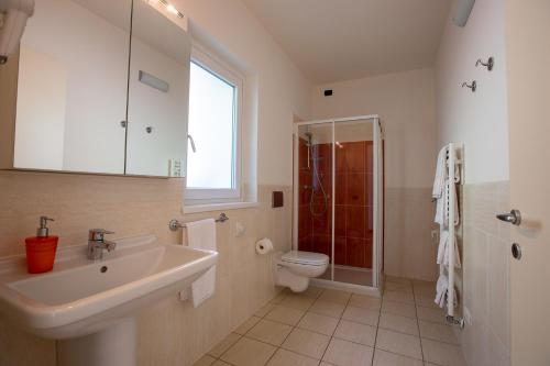 a bathroom with a sink and a toilet and a window at Residence CaFelicita - Apartments Lake View - Infinity Pool - Jacuzzi in Gravedona