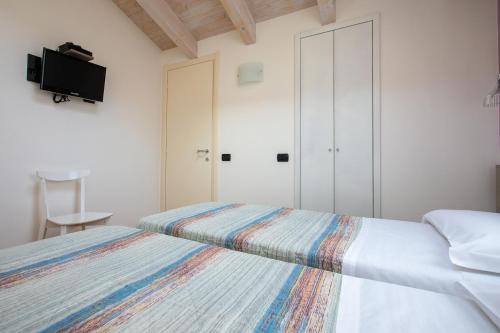a bedroom with two beds and a tv on the wall at Residence CaFelicita - Apartments Lake View - Infinity Pool - Jacuzzi in Gravedona