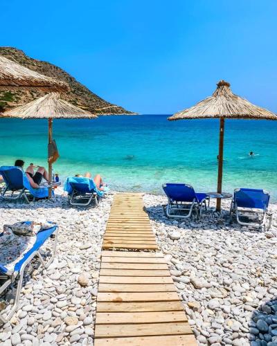 a pathway on a beach with chairs and umbrellas at Haroupia The Residence in Kalidhón