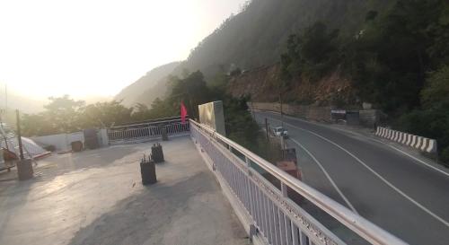 a road with a fence on the side of a mountain at KC Hotel & Restaurant in Rudraprayāg
