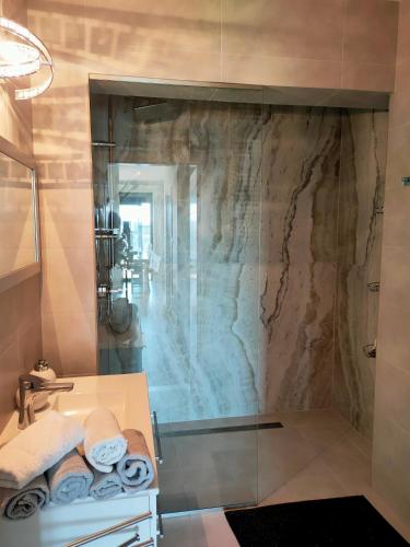 a bathroom with a shower and a sink with towels at AURA Delux Seaside in Dziwnów