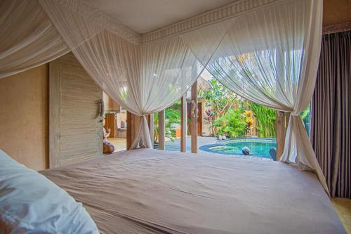 a bedroom with a bed with curtains and a swimming pool at Anahata - Tropical Private Villas in Gili Air