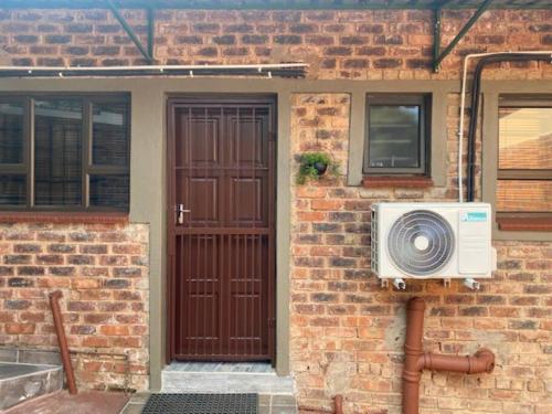 a brick house with a door and a fan at Short Term Rental Re-imagined in Johannesburg