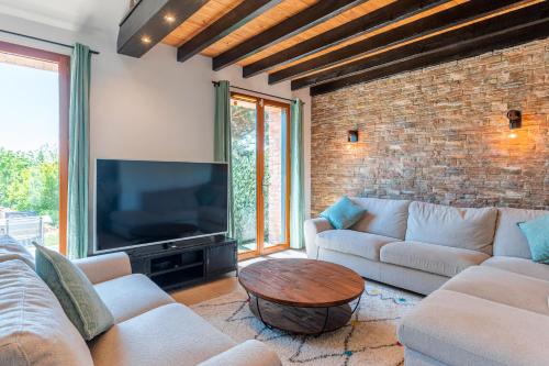 a living room with couches and a tv and a brick wall at Superbe maison avec piscine et jacuzzi dans les dunes in Ambleteuse