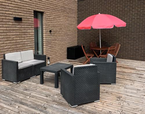 eine Terrasse mit Stühlen und einem Tisch mit einem Sonnenschirm in der Unterkunft Lu ptite cwane dol Lydie in Malmedy