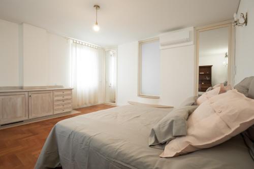a white bedroom with a large bed and windows at L'Andito in Carpi