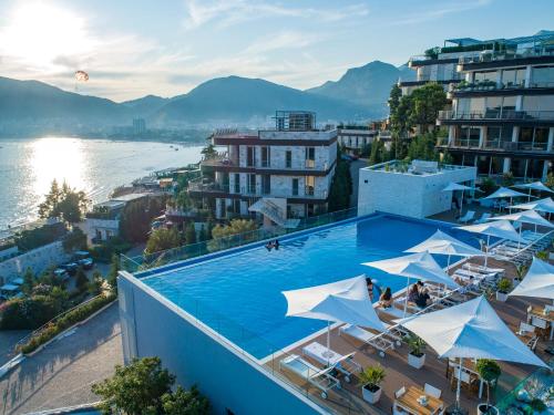 a large swimming pool with white umbrellas on a building at Dukley Hotel & Resort in Budva