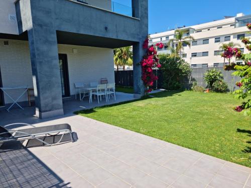 a patio with a grassy yard with a table and chairs at Residencial Costa Doñana (Sanlucar de Barrameda) in Sanlúcar de Barrameda
