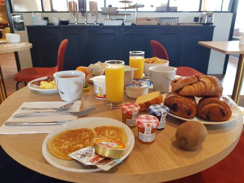 a wooden table with breakfast foods and drinks on it at Kyriad Carcassonne - Aéroport in Carcassonne