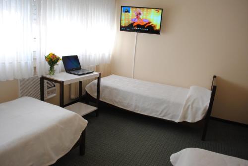 Habitación con 2 camas y escritorio con ordenador portátil. en San Marco Hotel en La Plata