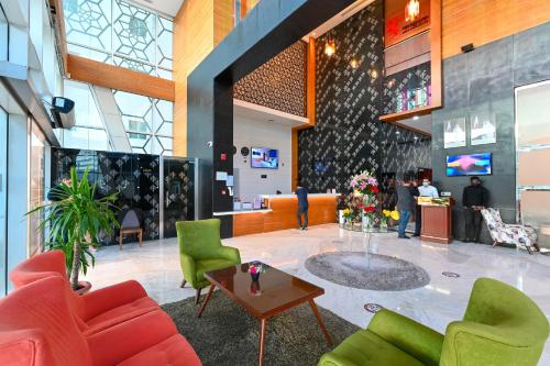 a lobby with green and red chairs and a table at Al Mansour Suites Hotel in Doha