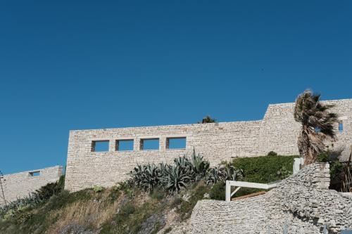 a brick building on a hill with a palm tree at Banfi's villa on the sea in Bisceglie