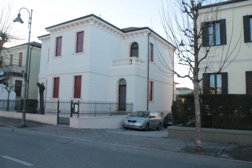 una casa bianca con una macchina parcheggiata di fronte di Ca' D'Agostino a Battaglia Terme